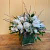 White rose arrangement in a square glass vase with greenery