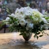 White floral arrangement in a glass vase with greenery