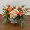 Peach and pink floral arrangement in a white pedestal vase