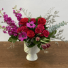 Red and pink flower arrangement in a white vase