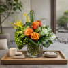 A modern, leaf-lined composition featuring Cherry Brandy roses, green hydrangea, cymbidium orchids