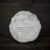 Round decorative plaque on a black stand with the words 