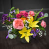 Mixed bouquet with pink roses, yellow lilies, and purple flowers in a vase