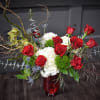 Red roses and white hydrangeas in a red vase with curly branches