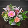 A bright cluster of pink lilies and  large pink gerbera daisies