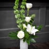 Pure white lilies and roses rise from tall green spikes in a