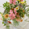 Mixed pastel flower arrangements in clear glass vases on a white tablecloth