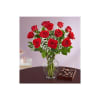 Red roses in a glass vase with a box of chocolates beside them