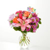 Pink and orange mixed bouquet in a clear glass vase with a Happy Birthday pick