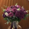Purple roses and hydrangeas in a glass vase with ribbon