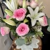 Pink roses and white lilies arranged in a clear glass vase