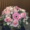 Pink roses and a gerbera daisy arranged in a square vase