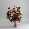 Bouquet of pink and red roses with a teddy bear in a glass vase