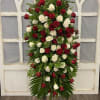 Tall standing arrangement of red and white roses on an easel