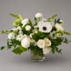 White floral arrangement in a clear glass vase with green accents
