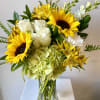 Glass vase of yellow sunflowers, white roses, green hydrangea, and mixed yellow and white flowers