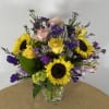 Mixed bouquet of sunflowers, yellow and pink roses in a clear glass vase
