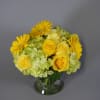 Yellow roses and gerbera daisies in a clear glass vase