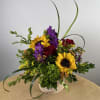 Bouquet of sunflowers, red roses, and purple flowers in a white basket