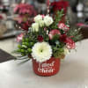 Mixed floral arrangement in a red container with white and red blooms