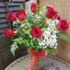 Red roses arranged in a clear glass vase with baby's breath