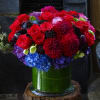 Bouquet of red, purple, and blue flowers in a green glass vase
