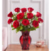 Red roses arranged in a red glass vase with white baby's breath