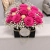 Hot pink roses in a black gift box with white filler flowers and gold chocolates
