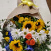 Bouquet of sunflowers, white daisies, and orange roses wrapped in brown paper