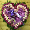 Heart-shaped floral tribute with pink and purple roses and hydrangeas