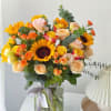 Bouquet of sunflowers and peach roses in a glass vase