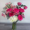Pink roses and mixed blooms arranged in a clear glass vase