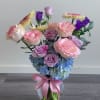 Pink and lavender roses with blue hydrangeas in a glass vase