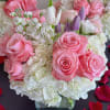 Pink roses and white hydrangeas with purple tulips in a glass vase