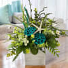Tropical floral arrangement in a white square vase with starfish accents