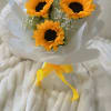 Bouquet of three sunflowers wrapped in white paper with a yellow ribbon