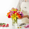 Colorful mixed bouquet in a clear glass vase with a large yellow lily