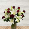 Bouquet of white lilies and deep red roses in a glass vase