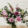 Pink lilies and mixed flowers arranged in a glass vase
