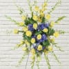 Yellow roses and purple flowers in a standing spray on an easel