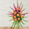 Orange roses and magenta flowers in a tall standing arrangement