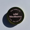 Round candle tin labeled wild blackberry on a light surface