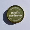 Round green candle tin with Pacific Northwest branding