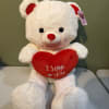 White teddy bear holding a red heart with "I love you" text