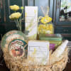 Gift basket with yellow flowers, decorative plates, and assorted packaged items