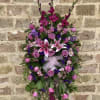 Standing floral spray with pink roses and lilies on a white easel