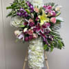 Large floral standing spray with lilies, roses, orchids, and white hydrangeas