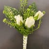 White rose boutonniere with speckled green leaves and ribbon wrap