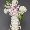 White floral cross arrangement with lilies, roses, and hydrangeas on an easel