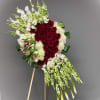 Standing floral spray with red roses and white flowers on an easel